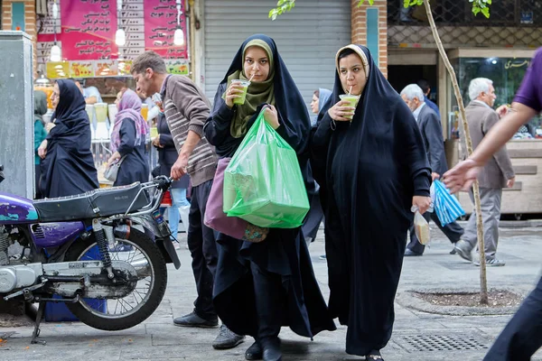 İki genç Müslüman kadın suyu içme sokakta, Tahran, Iran.