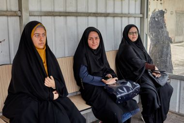 Siyah İslami giysiler içinde üç kız otobüs,: Kashan, Iran bekliyor.