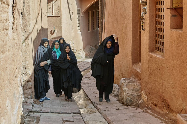 Iranian women at narrow street in village, Abyaneh, Iran.
