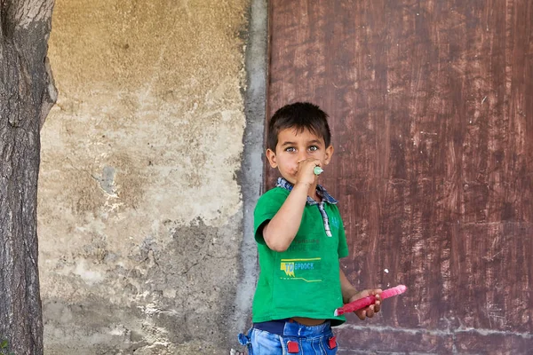 Malý chlapec saje lízátko proti zdi domu, Kashan, Írán. — Stock fotografie