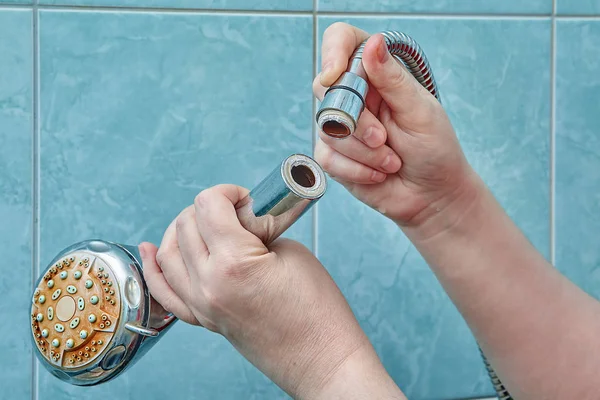 Hände halten einen Brausekopf, der sich vom Schlauch gelöst hat. — Stockfoto