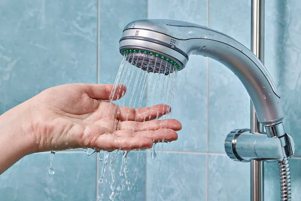 Flexibler Schlauch Brause an Halter geklemmt, Hand prüft Wassertemperatur — Stockfoto