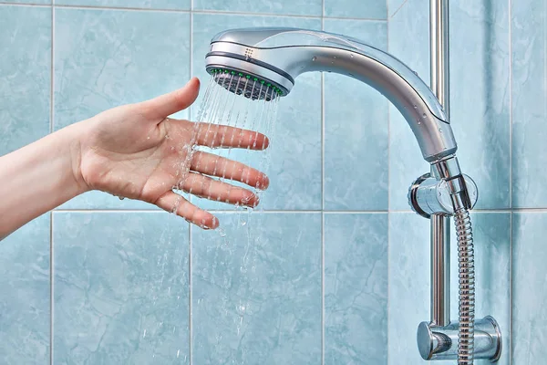 Frau ordnete ihre Hand in Wasserstrahl aus der Dusche. — Stockfoto