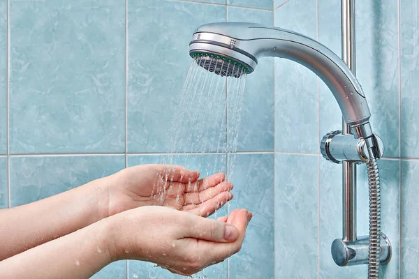 Zwei menschliche Handflächen unter Regenduschkopf mit Handsprüher. — Stockfoto