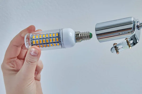 Mão segura uma lâmpada LED para instalação em luminária, close-up . — Fotografia de Stock