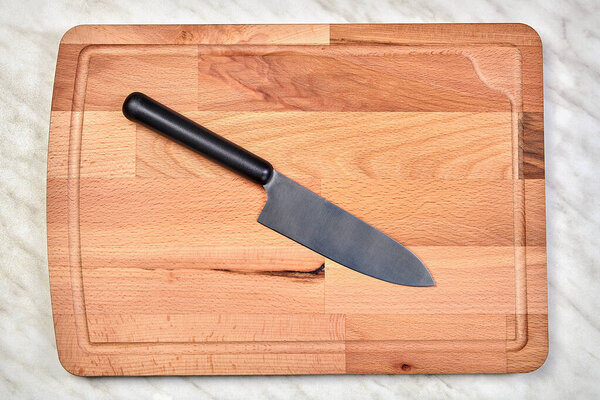 Cutting board made of birch wood and kitchen knife.