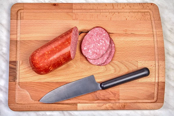 Sliced sausage and knife on a cutting board. — Stock Photo, Image