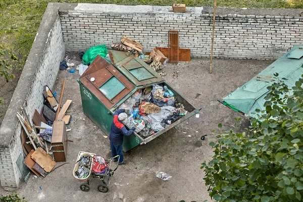 El mendigo hurga en un cubo de basura . — Foto de Stock