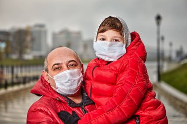 Baba ve oğul koruyucu tıbbi maske takıyor.