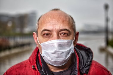 50 yaşın üzerindeki kel adam koruyucu bir tıbbi maske takıyor..