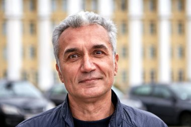 Mature handsome man is posing outdoors.