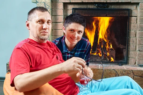 Mature couple are siting near fireplace. — Stock Photo, Image