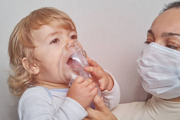 Woman helps daughter to breathe with mask. — Stock Photo, Image