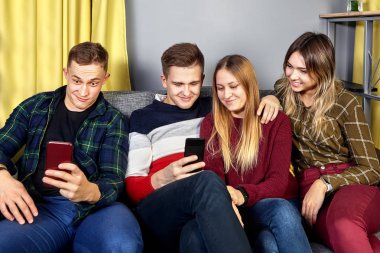 Genç kadınlar ve erkekler telefon ekranlarına bakıyorlar..