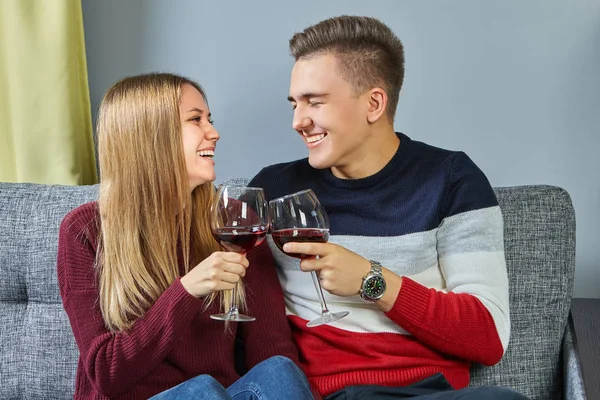 Young man and woman laugh and clink alcohol.