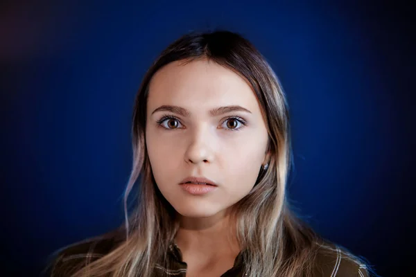 Portret van een jonge vrouw op een donkerblauwe achtergrond. — Stockfoto
