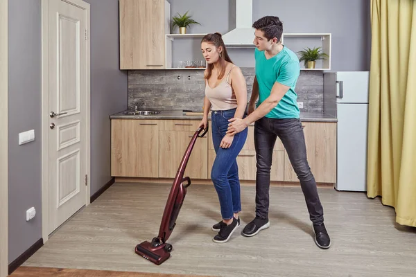 Sexual harassment, discrimination and sexism in workplace. Employer violence over employee A white man pestering a beautiful young maid woman who is vacuuming kitchen floor using a vacuum cleaner.