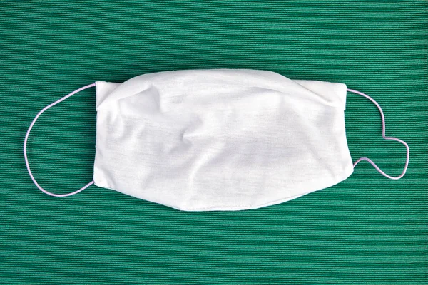 Cloth bandage or face mask to protect the respiratory system during the covid-19 pandemic, on a green background. Reusable microfiber facemask, subject to daily washing.