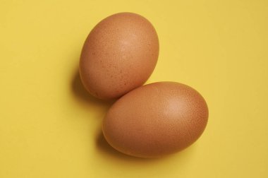 Sarı arka planda iki sarı tavuk yumurtası.