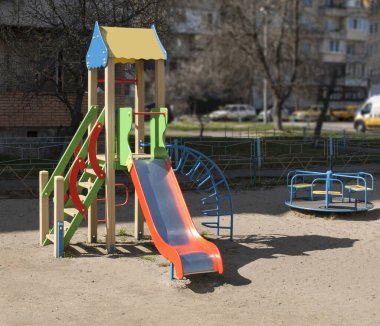 Parlak güneşin altında, konut binalarının yanındaki oyun parkı