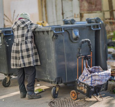 Şehir dilencisi çöp tenekesinde arama yapıyor.