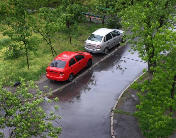 Two cars near the house get wet in the rain