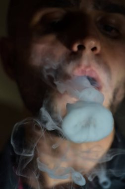 Çapkın gençler. Genç yakışıklı adam, Vape Bar 'da elektronik sigara içiyor. Kötü alışkanlık sağlığa zararlıdır. Buhar etkinliği.