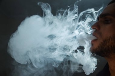 Çapkın gençler. Genç yakışıklı adam, Vape Bar 'da elektronik sigara içiyor. Kötü alışkanlık sağlığa zararlıdır. Buhar etkinliği.