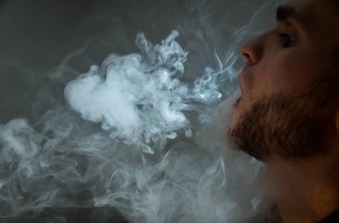 Çapkın gençler. Genç yakışıklı adam, Vape Bar 'da elektronik sigara içiyor. Kötü alışkanlık sağlığa zararlıdır. Buhar etkinliği.