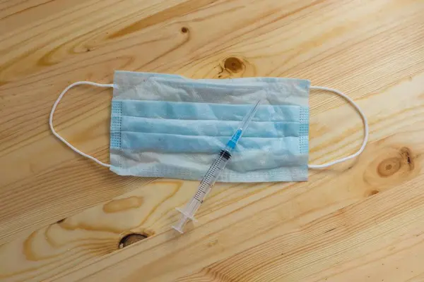Masada tıbbi koruyucu maske ve şırınga var.