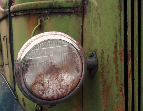 Close up of the headlight of an old abandoned truck with rusted green grille and panels — Stock Photo, Image