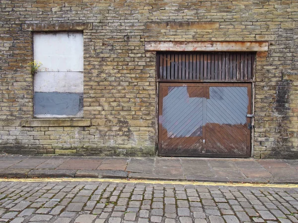 Вид спереду на стару покинуту дерев'яну індустріальну власність на порожній вулиці з піднятим вікном і розкладеними цегляними стінами — стокове фото