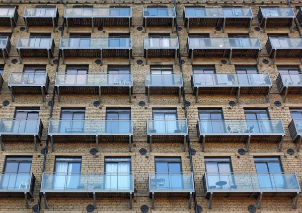 Фасад большого здания старой каменной мельницы, переоборудованного в квартиры с современными стеклянными балконами — стоковое фото