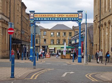 the metal outdoor gate of huddersfield open market area and building in byram street with shops stalls and pedestrians
