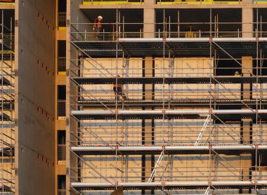 builders working on scaffolding and platforms on different floors of a large modern construction site