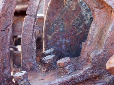 a close up of rusted iron connecting rods and gears with bolts on old corroded machinery