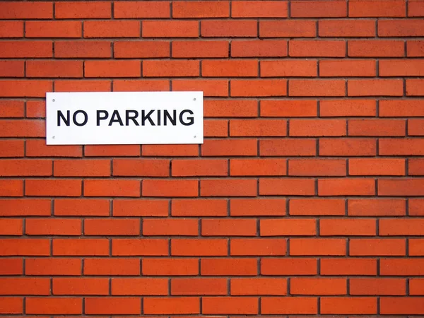 Un letrero blanco que dice que no hay estacionamiento en una pared de ladrillo rojo —  Fotos de Stock