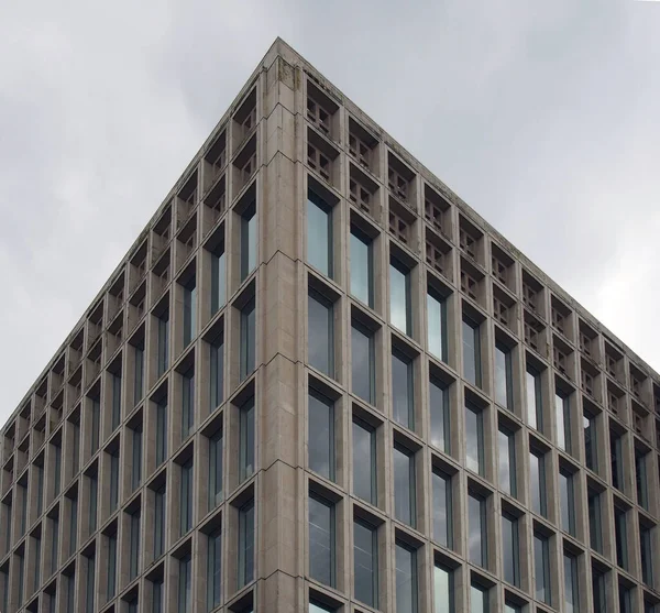 60 년 대의 전형적 인 브루 티즘 스타일의 코너 세그먼트 콘크리트 사무실 건물과 희미 한 구름 하늘에 대한 기하학적 인 콘크리트 뼈대 — 스톡 사진