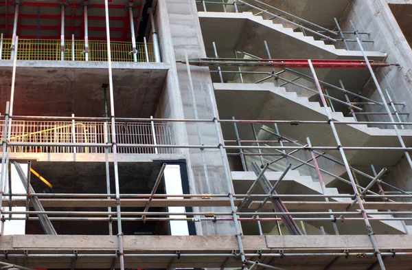 Sluiten van een betonnen gebouw in aanbouw omgeven door steigers met blootgestelde trappen en vloeren — Stockfoto