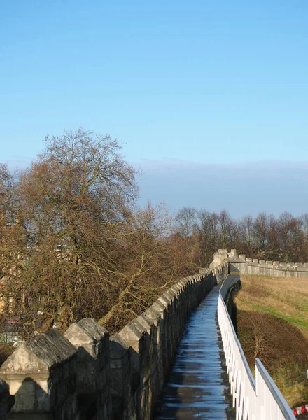 A view along the pedestrian walkway on historic medieval city walls in york surrounded by trees and city buildings — 图库照片