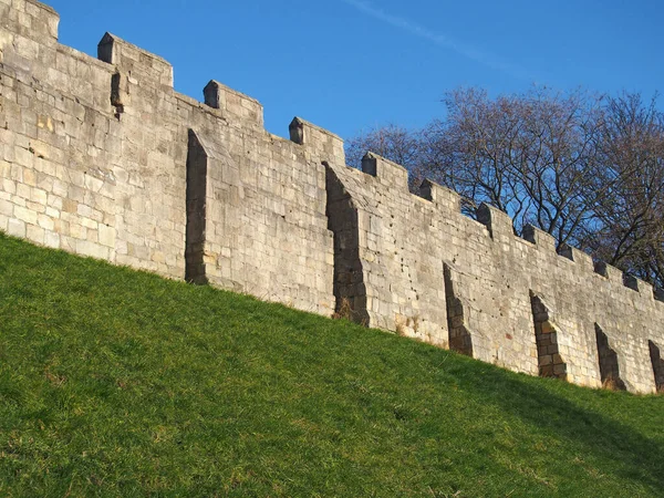 A view of the ancient medieval city walls of york with grass covered embankment and blue sky — 图库照片