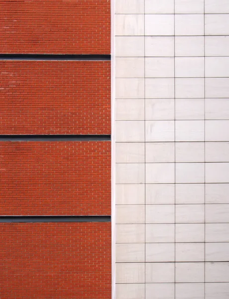 a brick red brick wall with black lines divided in half by large white modern stone tiles