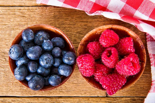Blueberries and raspberries in the wooden dish — Stock Photo, Image