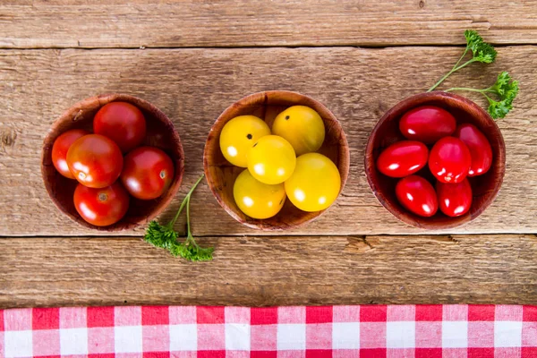 Red and yellow tomatoes with parsley on wooden background — Stock Photo, Image