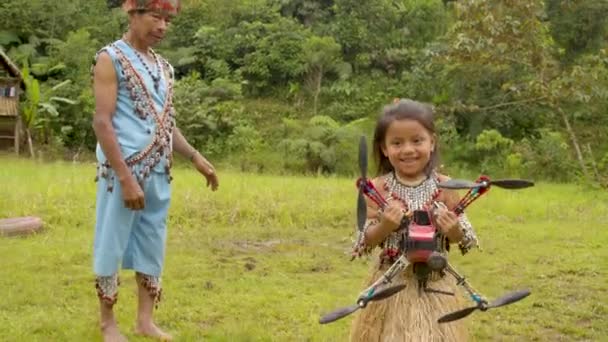 Pequeña chica indígena corre hacia su padre para entregarle un dron — Vídeo de stock