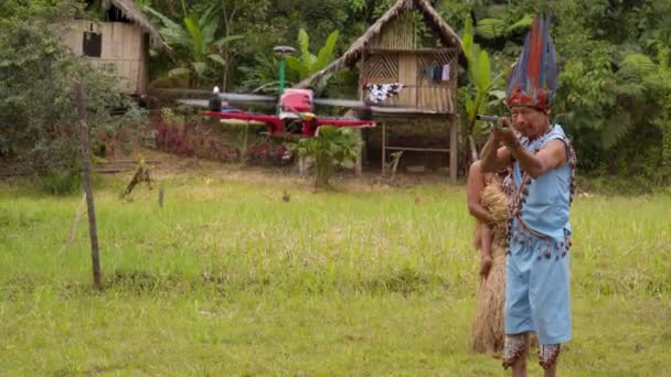 Homem indígena usar sua arma de fogo para proteger sua aldeia de um drone voador — Vídeo de Stock