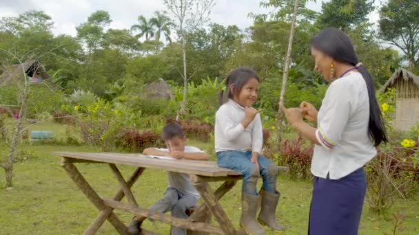 Коренная женщина помогает детям с их домашней работой — стоковое видео