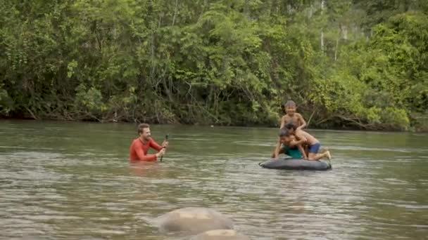 Filmmaker está usando seu Gopro para filmar crianças indígenas brincando em uma água — Vídeo de Stock