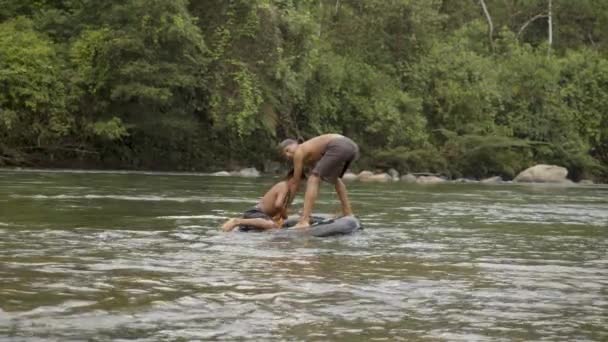 Två inhemska pojkar leker i ett vatten med ett flytande däck — Stockvideo