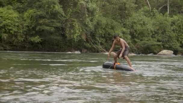 Domorodý chlapec hraje ve vodě s plovoucí pneumatikou — Stock video